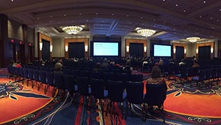 annual meeting ballroom with rows of chairs and screens