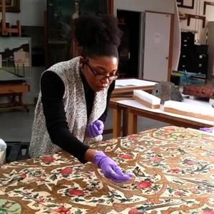 Ariana Smith surface cleans a fragment of a Qajar-era painted ceiling at the Brooklyn Museum